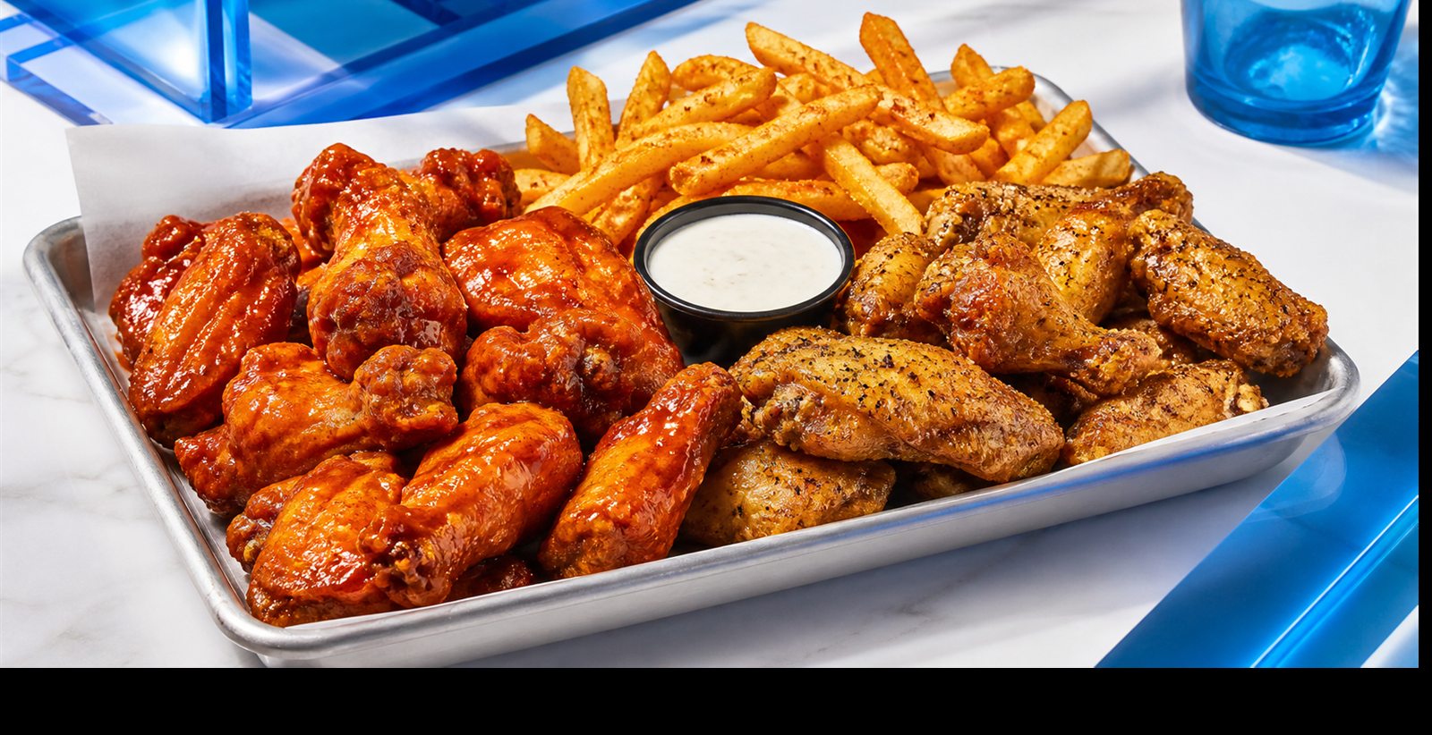 Tray of crispy buffalo and lemon pepper wings with seasoned fries and ranch